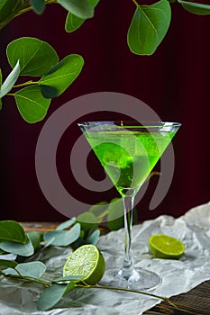 A green drink with ice cubes in a glass for mojito on crumpled w