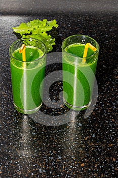 Green drink made from fresh herbs with chlorophyll in glasses on a black table surface