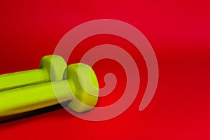 Green dumbbells isolated on a red background. Flatlay concept of fitness, gym and healthy lifestyle. The view from the top and