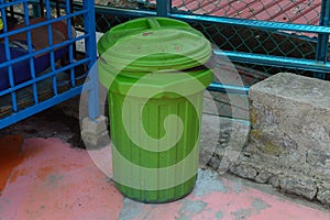 Green dustbin on the floor at the roadside