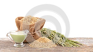 Green ears of rice , seeds and milk on an old wood table isolated on white background
