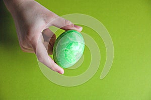 Green Easter egg in children`s palms