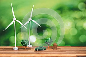 Green eco car and windmill turbine model on office table design. Alter