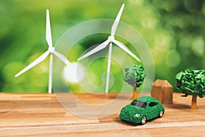 Green eco car and windmill turbine model on office table design. Alter