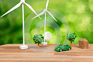 Green eco car and windmill turbine model on office table design. Alter