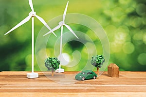 Green eco car and windmill turbine model on office table design. Alter