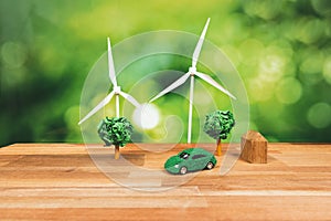 Green eco car and windmill turbine model on office table design. Alter