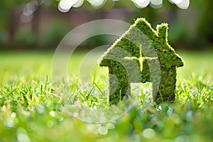 Green eco house symbol on green grass with bokeh background. Ai generated