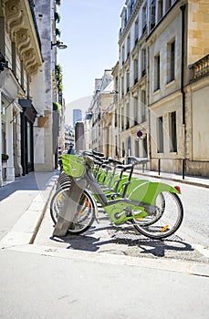 Green ecological electric bicycles with baskets for public rent await tourists cyclists on the streets of Paris