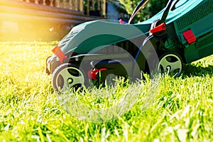 Green electric lawn mower on a freshly mown lawn in the garden