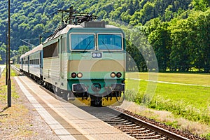 A green electric locomotive passing the Czech countryside