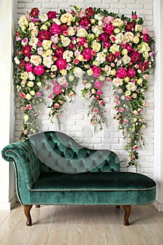 Green elegant sofa in front of the wall of flowers photo