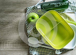 A green empty lunch box wrapped on wooden table , top view or o