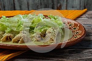 Green Enchiladas with lettuce served in a clay dish