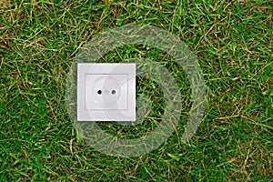 Green energy concept: electric outlet on a grass