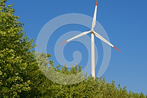 Green energy. Windmill in tree branches on blue sky background.renewable energy.Alternative energy sources