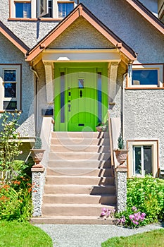 Green entrance door of family house under the porch with the doorsteps in front