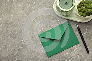 Green envelope, pen and candle on grey background