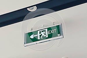 Green exit sign with white icon symnol hanging on the ceiling