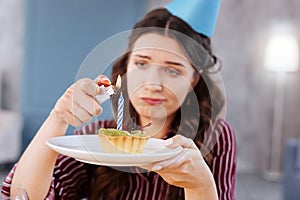 Green-eyed woman holding little birthday cake