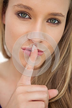 Green-eyes young woman with a finger on the lips