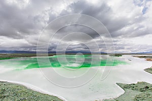 Green Feicui lake with dark clouds in sky in Qinghai province of China