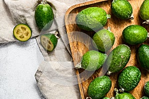 Green feijoa fruits in a wooden plate on  a grey background. Tropical fruit feijoa. Top view