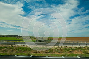 Green feilds and highway mooving cars veiw from side. The road along fields and forests