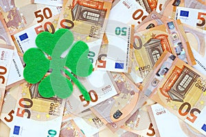 Green felt four leaf clover on 50 fifty euro banknotes background. Lucky talisman. Saint Patricks day.