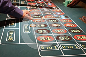 Green felt roulette table with players placing bets