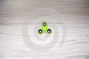 Green fidget spinner gadget isolated on grey wooden table. Background