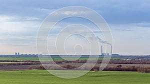 Green field on the background of urban industrial zone