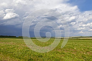 Green field and blue sky. Beautiful view of the grass and the hills on a sunny summer day.