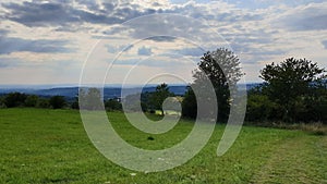 Green field in Hoherodskopf - Vogelsberg under cloudy sky photo