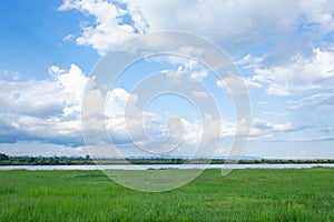 Green field, river and blue sky with light clouds backgrund