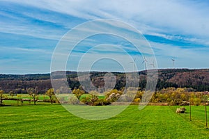 Green field with wind turbines on the background under the white sky