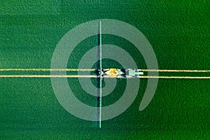 Green Fields. Aerial view of the tractor spraying the chemicals on the large green field. Agricultural spring background