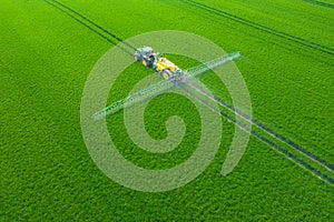 Green Fields. Aerial view of the tractor spraying the chemicals on the large green field. Agricultural spring background