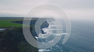 Green fields and amazing view of Cliffs of moher taking video using a drone from the air , beautiful landscape around.