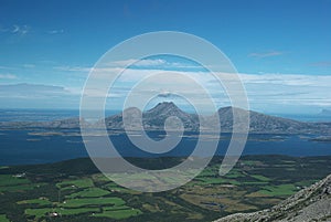 Green fields at the coastline of Alsten island from hiking trail in Seven Sister mountains