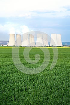 Green fields with cooling towers of nuclear power plant in background