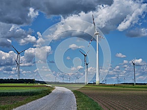 Green fields, road and metal windmills to generate electricity