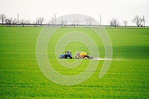 Green fields in spring. Tractor performs spring field work.