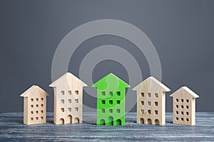 Green figure of a residential building stands out among rest of houses. Zero carbon emissions conservation energy saving