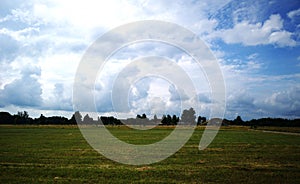 green filed under blue skies with white clouds