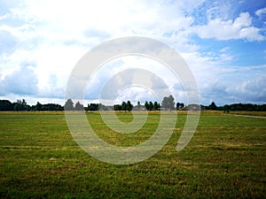 green filed under blue skies with white clouds