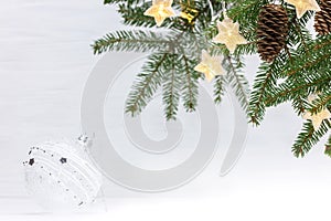 Green fir tree branch with star garland lights and decorative glass ball. christmas festive background