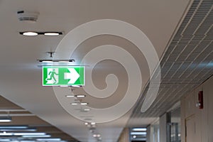 Green fire escape sign hang on the ceiling in the office.