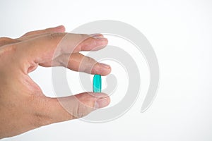 The green fish oil capsules in man's finger tip, isolated