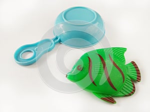 Green Fish toy and kitchenware made from plastic on white background